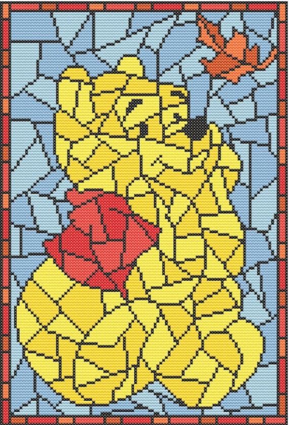 a cross stitch pattern with a yellow bear holding a red heart in it's paws