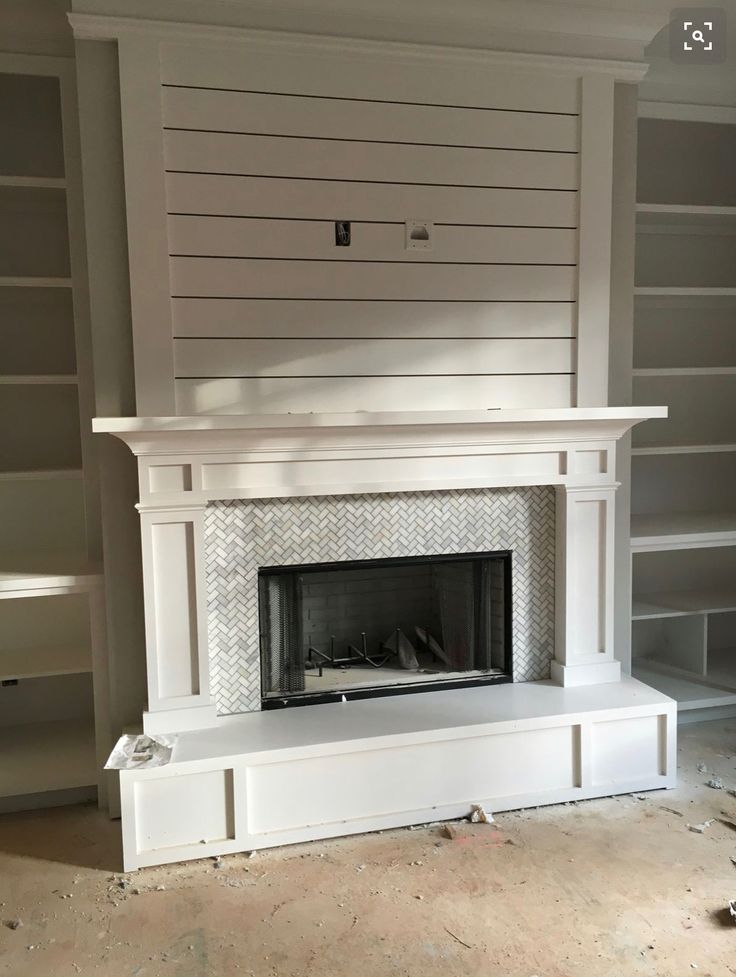 an empty fireplace in a room with no one around it and shelves on either side