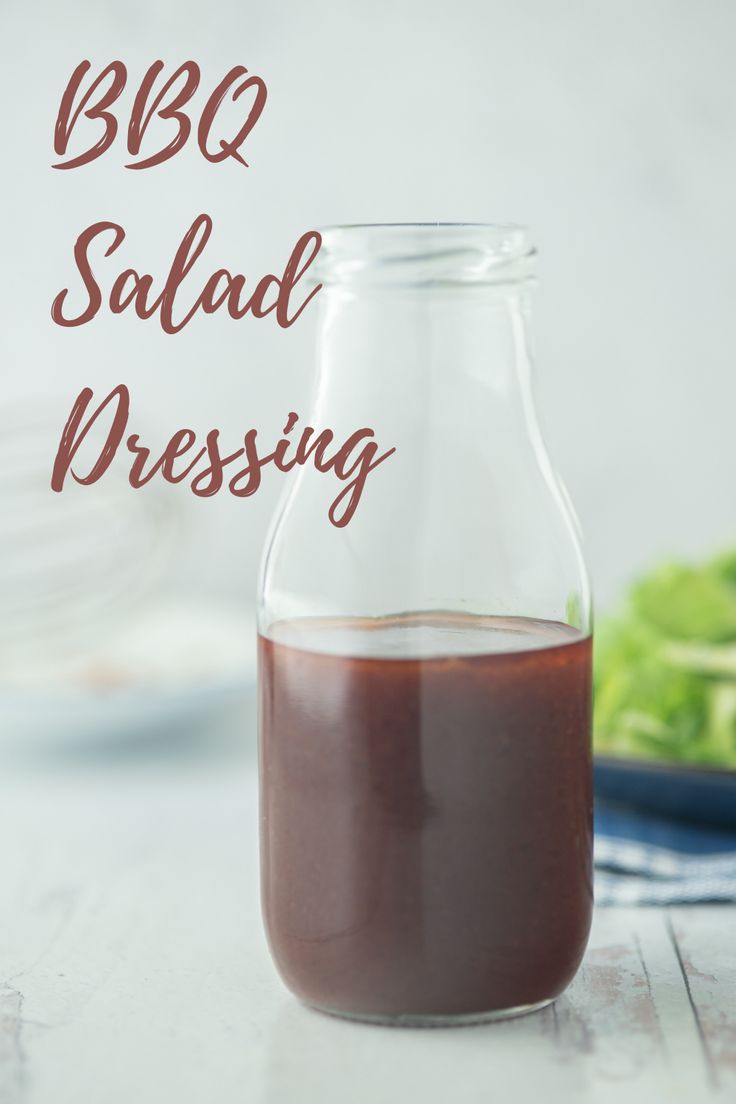 a bottle filled with red liquid sitting on top of a table next to broccoli