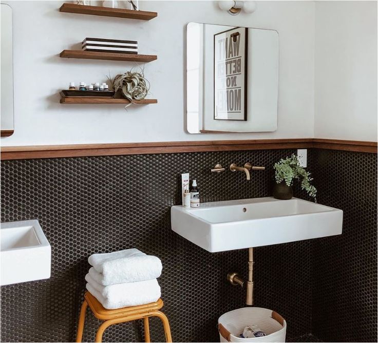 a white sink sitting under a bathroom mirror next to a blue stool and shelf filled with towels