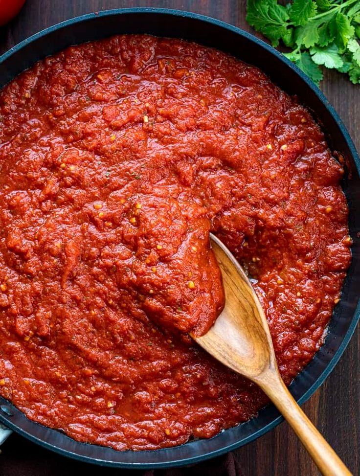 a wooden spoon in a pan filled with marinara sauce