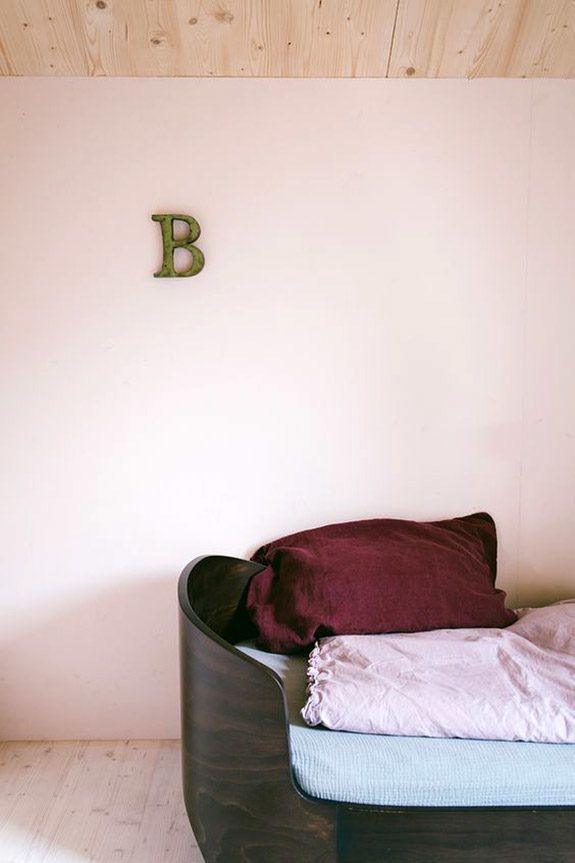 a bed sitting in the corner of a room next to a wall with a wooden letter on it