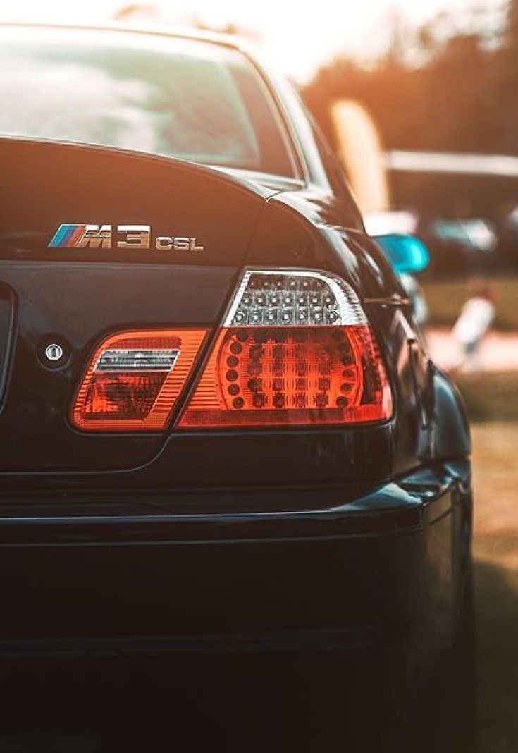 the back end of a black car parked in a parking lot