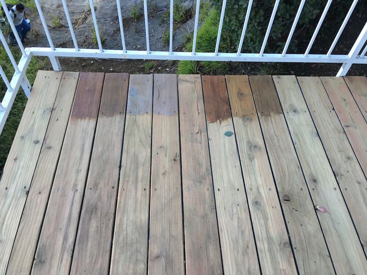 a wooden deck with white railings next to trees