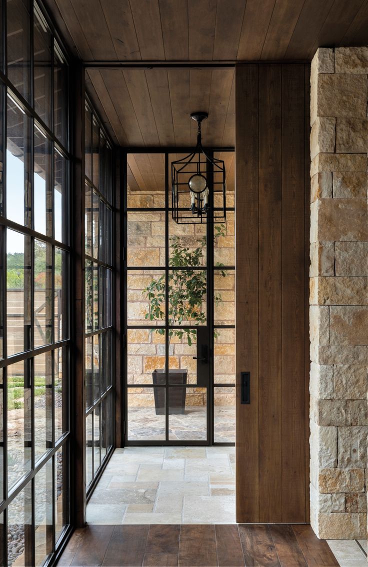 an open door leading into a room with large windows and wood paneling on the walls