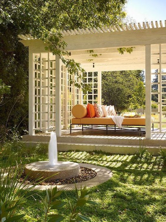 an outdoor seating area with white pergols and orange pillows