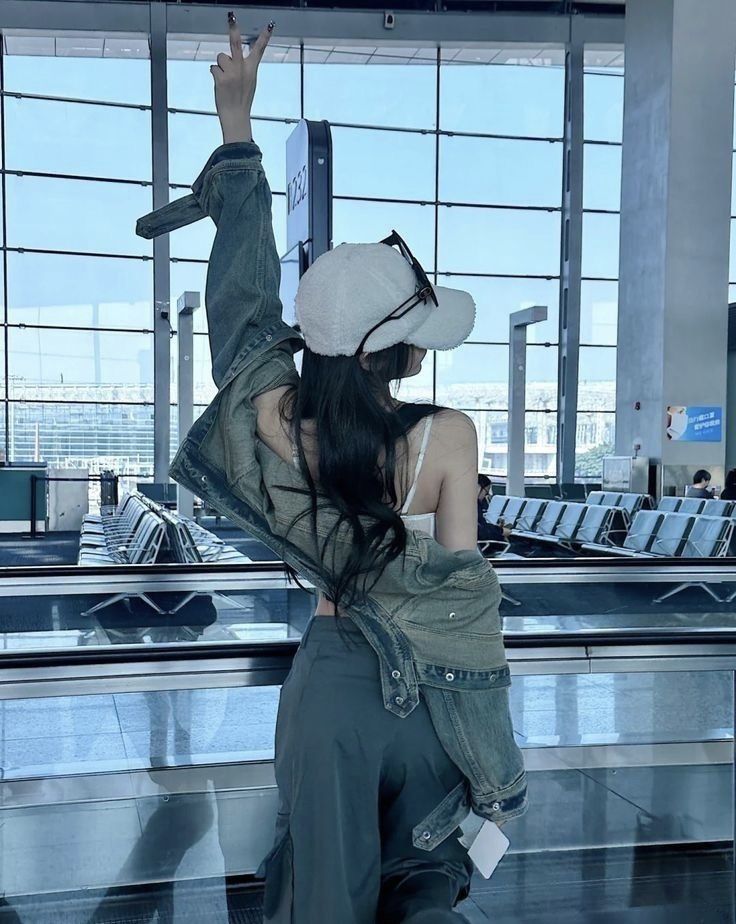 a woman sitting in an airport with her back to the camera and arms outstretched up