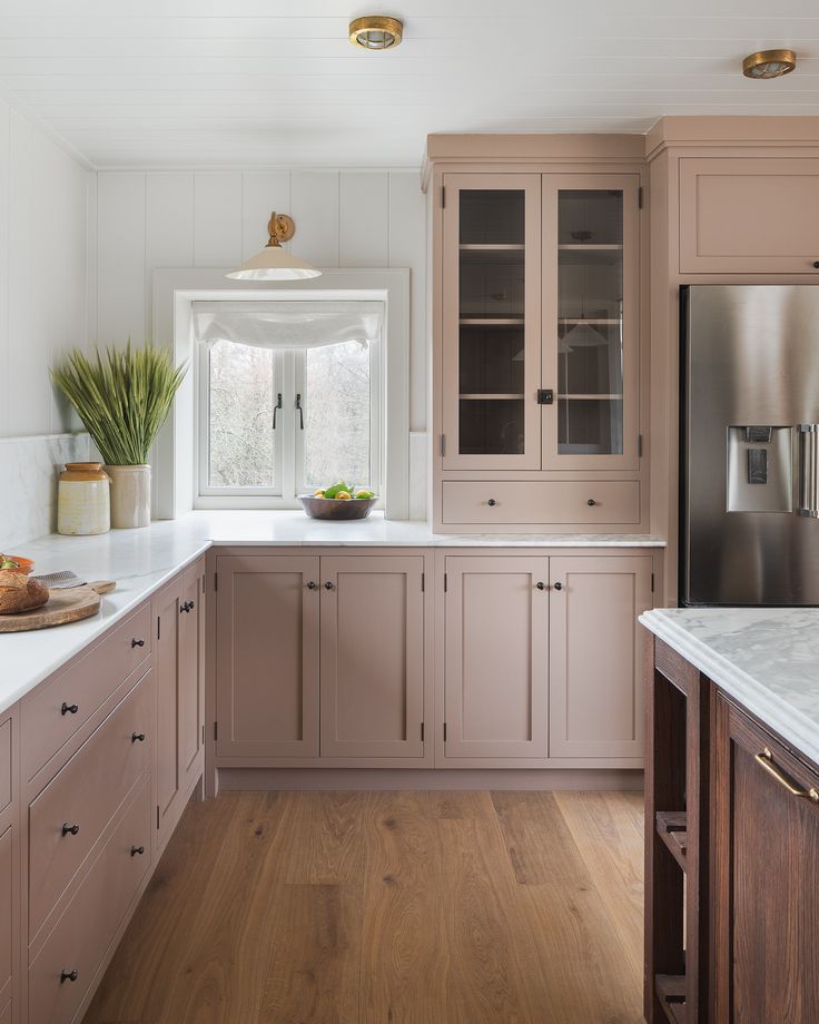 a large kitchen with wooden floors and cabinets in the center, along with white counter tops