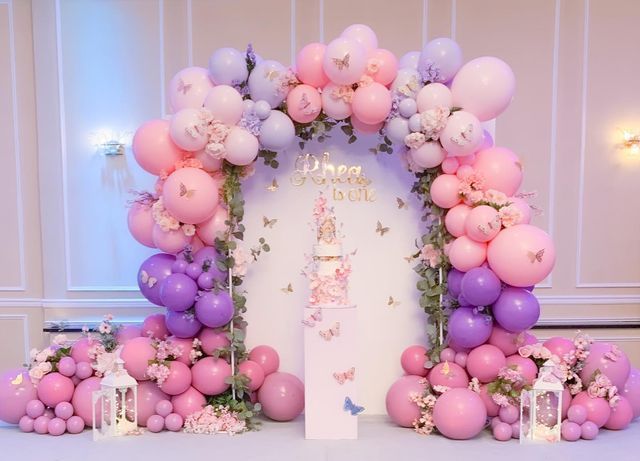 balloons and flowers decorate the entrance to a birthday party