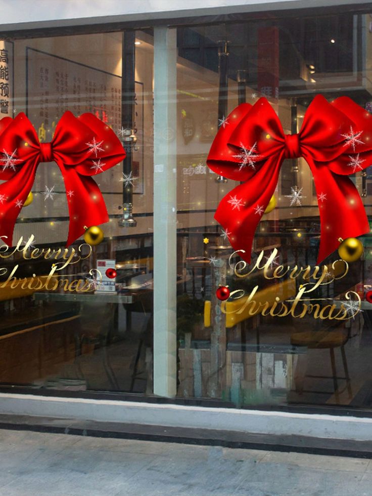 a store front window decorated for christmas with red bows and snowflakes on it