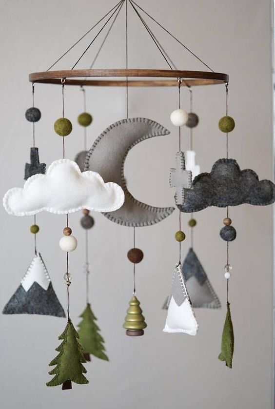 a mobile with clouds, mountains and trees hanging from the ceiling in front of a white wall