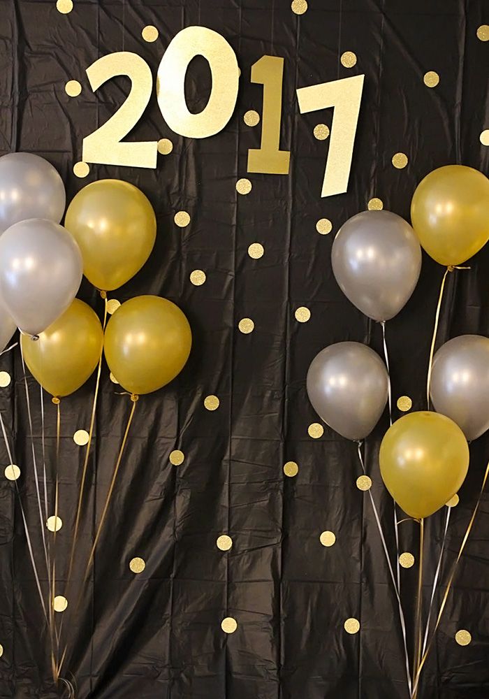 balloons and streamers are arranged in front of a black backdrop with gold polka dots