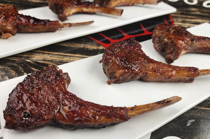 two white plates topped with ribs covered in bbq sauce