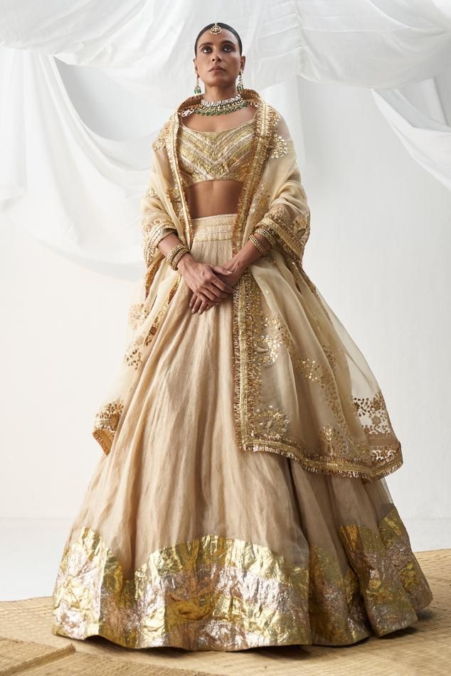 Beige attached cancan lehenga with zigzag lampi work. Comes with lampi gota sleeveless padded blouse and an organza gota patti embroidered dupatta.
Components: 3
Pattern: Embroidered
Type Of Work: Gota
Neckline: U-Neck
Sleeve Type: Sleeveless
Fabric: Lampi
Color: Beige
Other Details: 
Padded blouse
Attached cancan lehenga
Kiran lace dupatta
Approx. product weight (in kgs): 6
Length:
Blouse: 13 inches
Lehenga: 44 inches
Occasion: Wedding - Aza Fashions Gota Patti Lehenga, Orang India, Bridal Suits, Blouse Lehenga, Gold Lehenga, Black Kurta, Raw Silk Lehenga, Anamika Khanna, Diana Penty