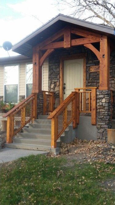 a house with stone and wood sidings on the front porch, stairs leading up to the entry door