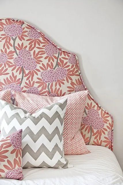 a bed topped with lots of pillows on top of it's headboard in a bedroom