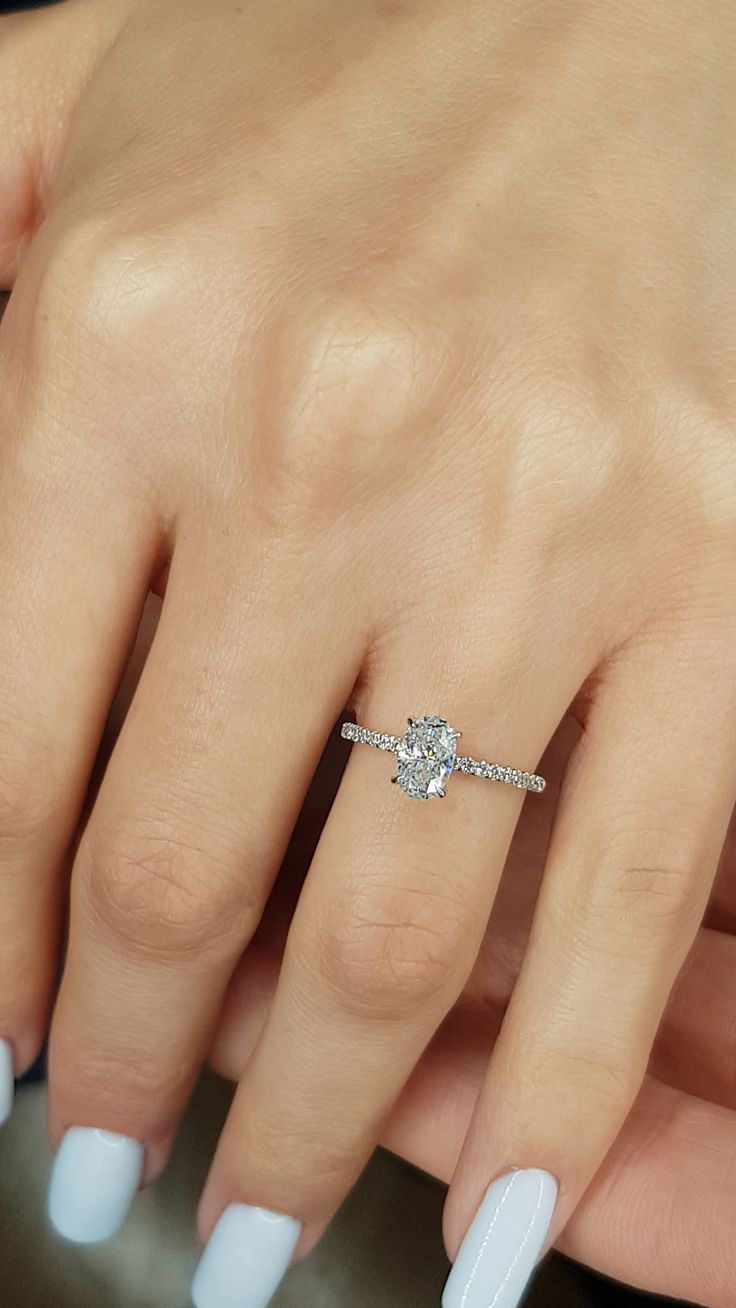 a woman's hand with white manicured nails and a diamond ring