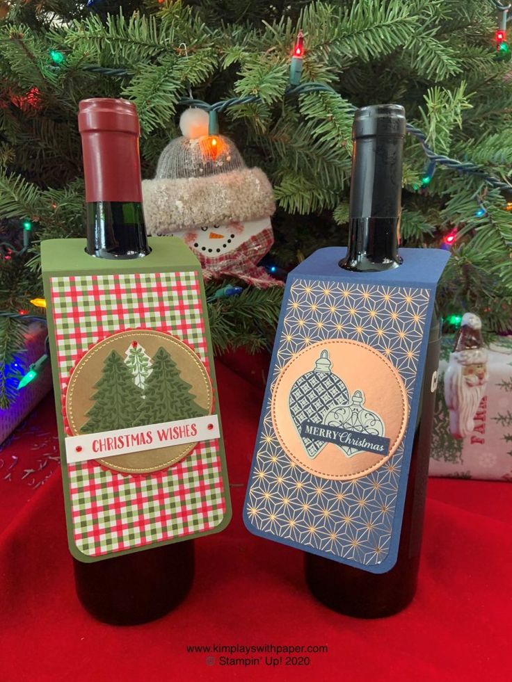 two wine bottles sitting next to each other near a christmas tree