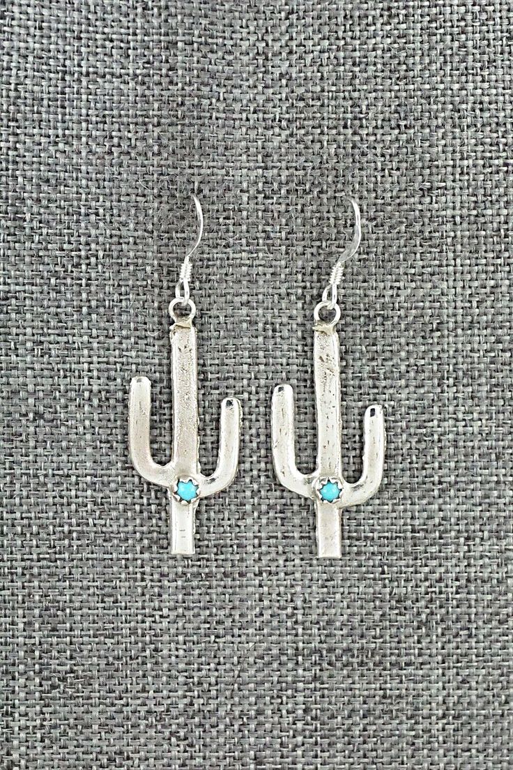 These turquoise and sterling silver cactus-shaped earrings were made by Navajo silversmith Sylvia Chee.Length: 1 3/4"Width: 3/4"Free shipping on all orders! We ship with USPS and always include tracking. All orders ship within a day of payment.Returns are accepted up to 30 days after you receive your order. Just send us a message. Our shop offers cash back or store credit. The item must be returned in new condition. Southwestern Sterling Silver Earrings With Ear Wire, Western Style Dangle Earrings For Pierced Ears, Southwestern Sterling Silver Dangle Earrings, Silver Dangle Western Earrings, Nickel Free Sterling Silver Western Earrings, Turquoise Nickel-free Western Earrings, Western Turquoise Nickel-free Earrings, Western Style Nickel-free Turquoise Earrings, Turquoise Dangle Earrings Western Style