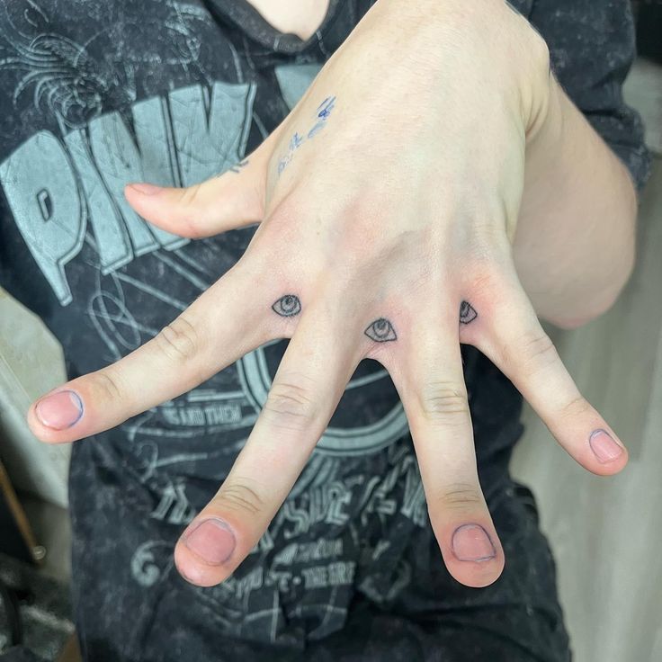 a person's hand with three small tattoos on it