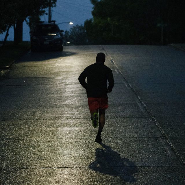 a man running down the street at night with his back turned to the camera,