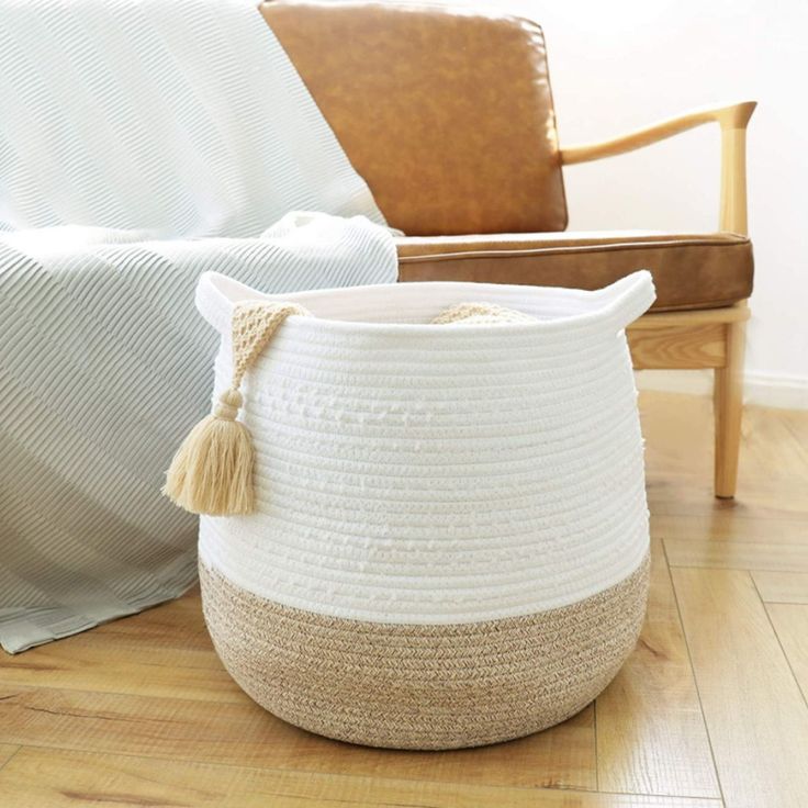 a large white basket sitting on top of a wooden floor next to a brown chair