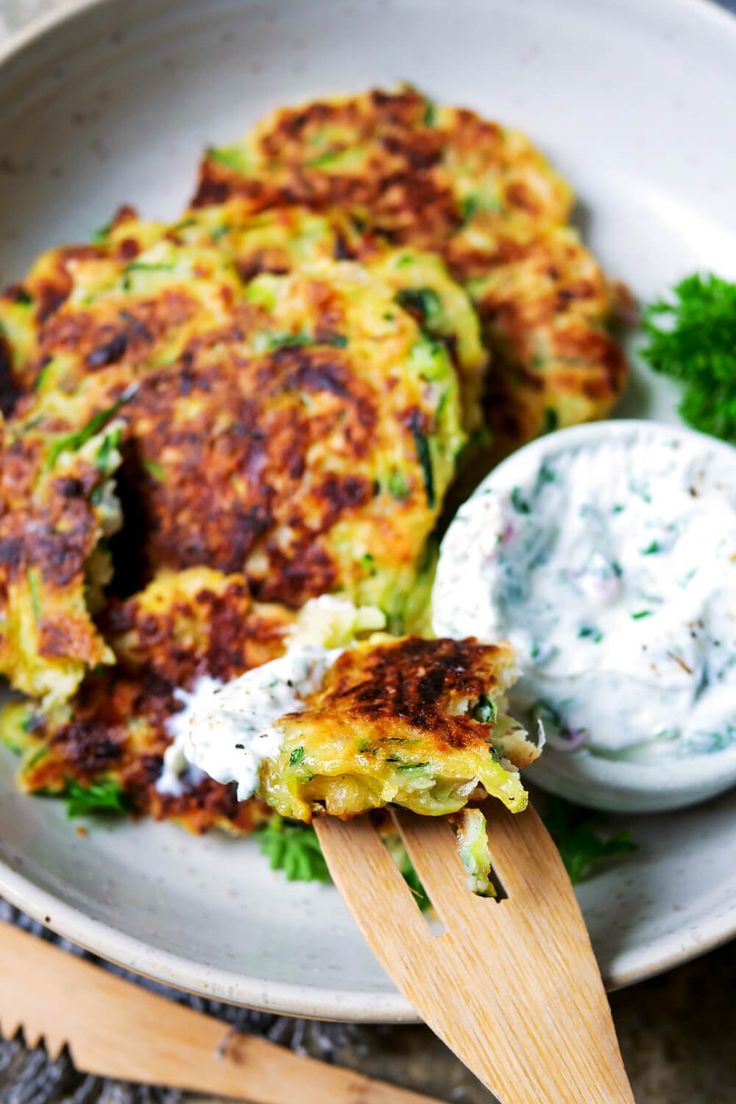 a close up of a plate of food with broccoli fritters and sour cream