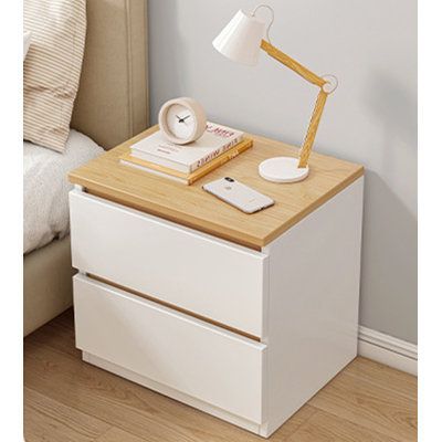 a nightstand with a lamp on top of it next to a bed