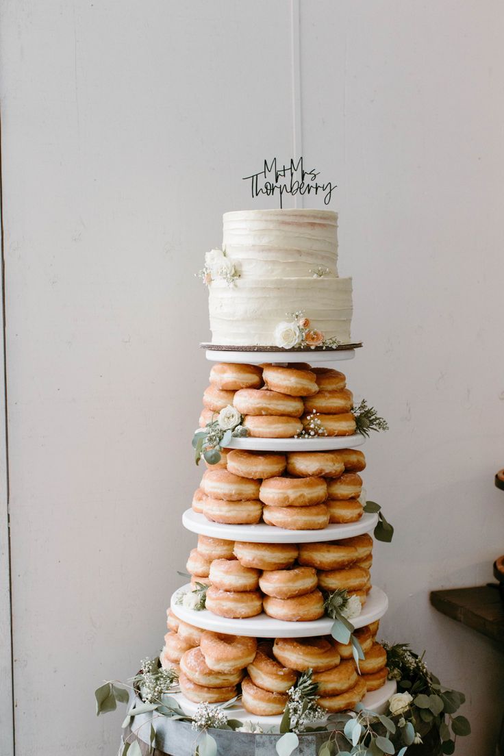 a tall stack of donuts sitting on top of a table next to a cake