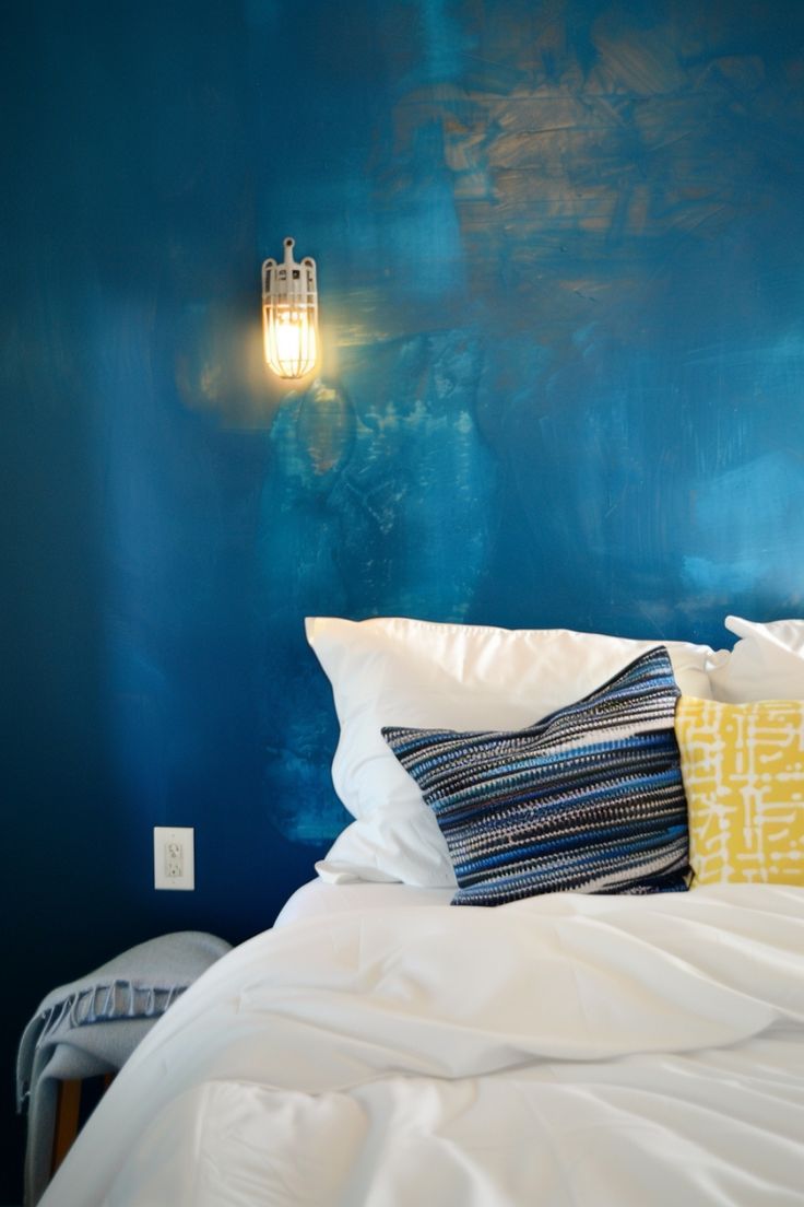 a bedroom with blue walls and white bedding