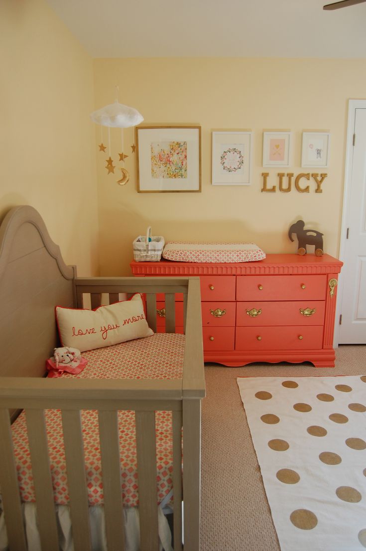 a baby's room with yellow walls and pink dressers in the corner, including an orange crib