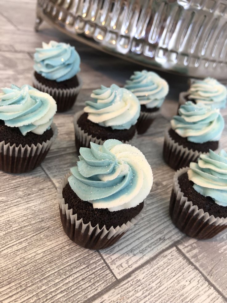 cupcakes with blue frosting sitting on a table