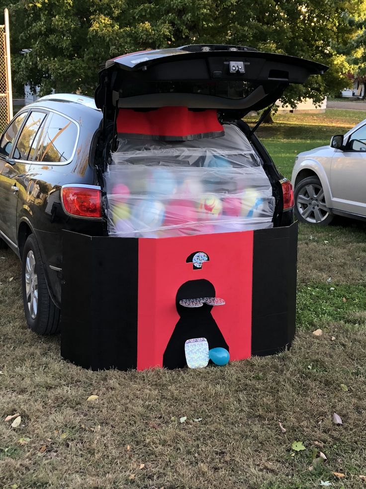 an inflatable cooler is sitting on the grass next to a car with its hood open