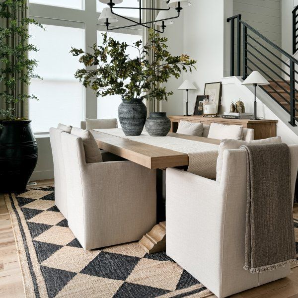 a dining room table surrounded by chairs and vases