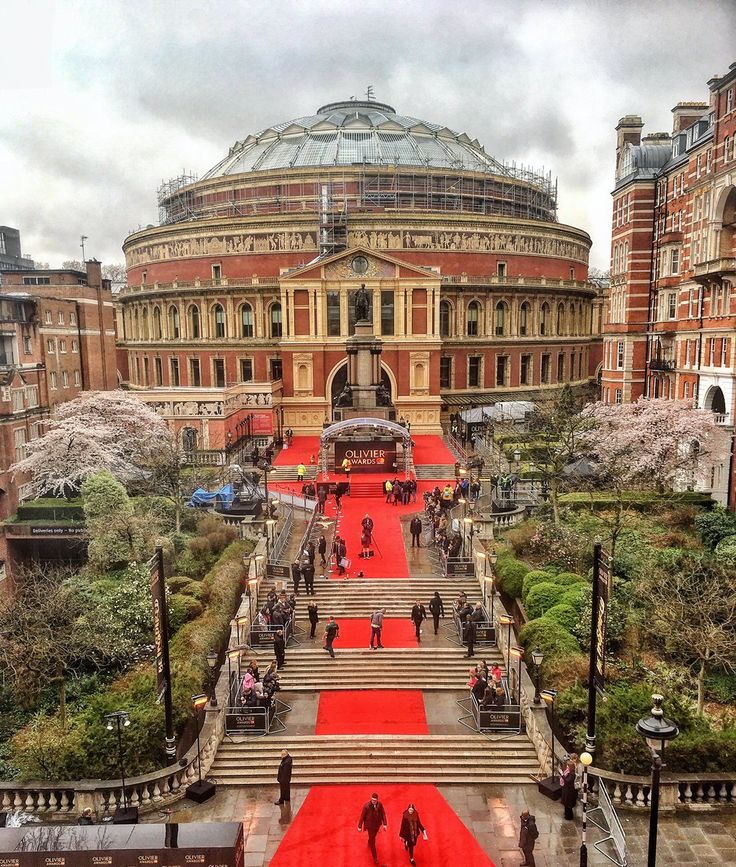 people are walking up and down the red carpeted stairs in front of an ornate building