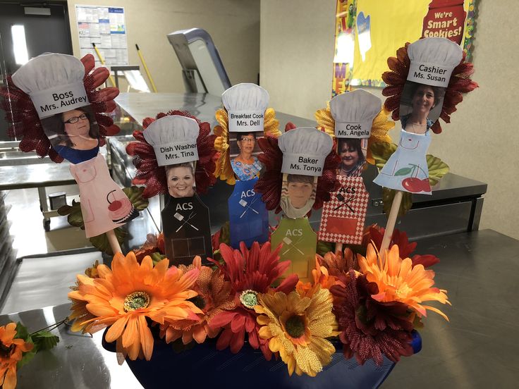 a group of people wearing chef hats on top of a table with fake flowers in front of them