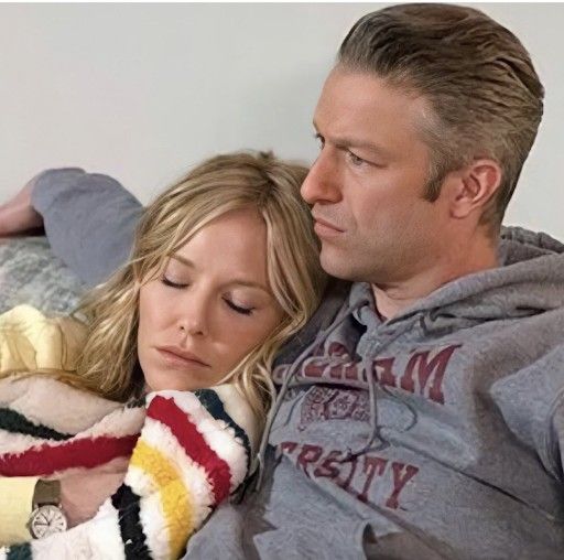 a man sitting next to a woman on top of a bed with her arms around him