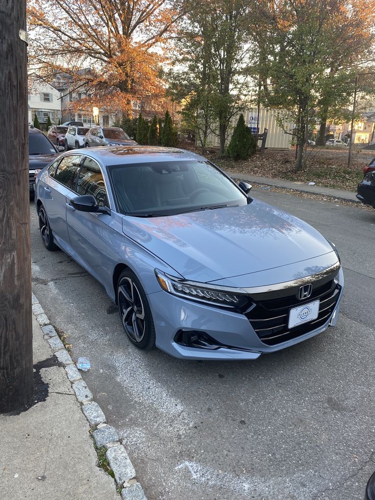 a silver car parked on the side of a road next to a pole and tree