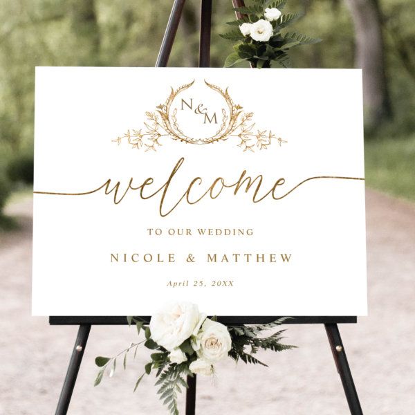 a welcome sign with flowers and greenery on it