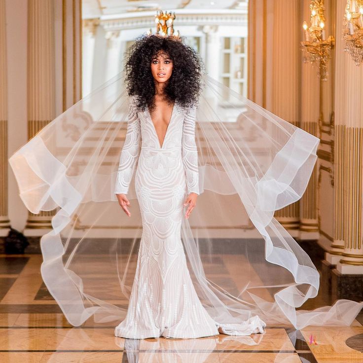 a woman in a white wedding dress with a veil on her head and long hair