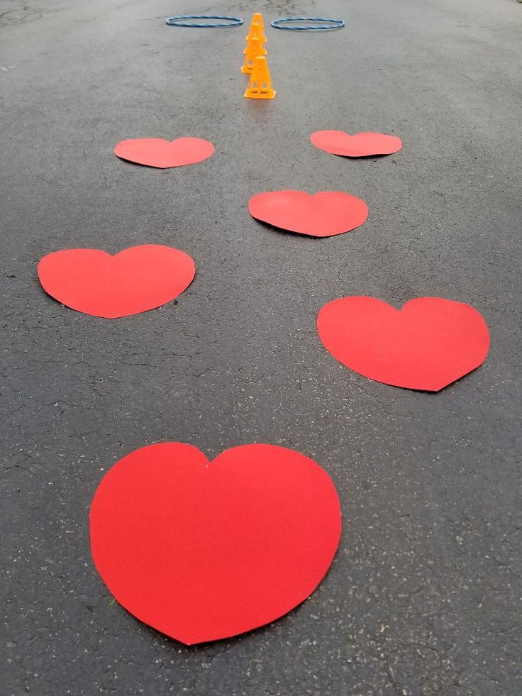 red hearts are arranged on the asphalt near yellow cones