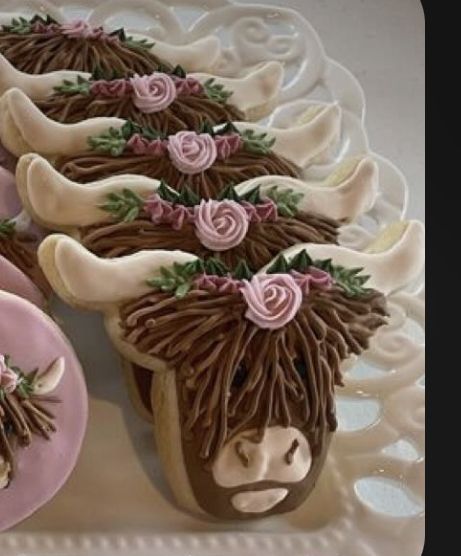 there are some cookies decorated like cows on a plate with pink frosting and flowers