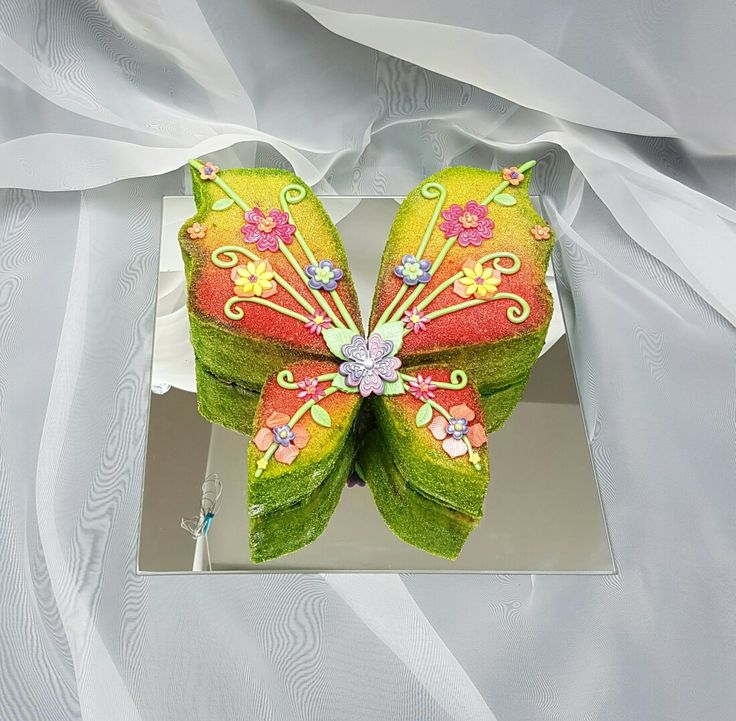 a green and red butterfly shaped object on a white surface