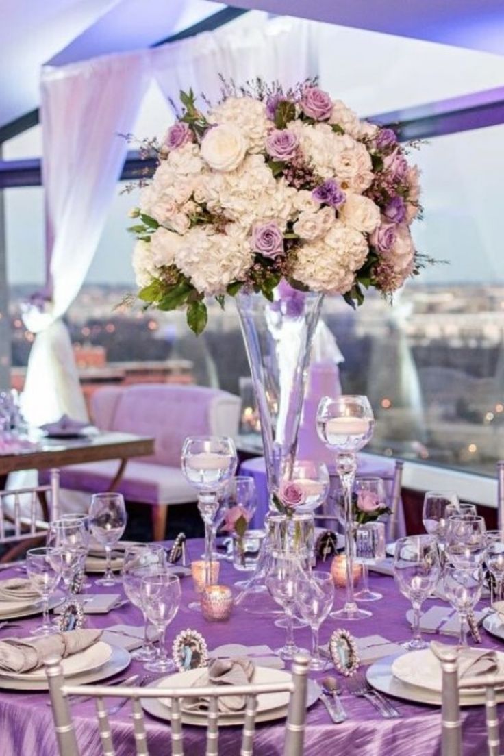 the table is set with purple linens and white flowers