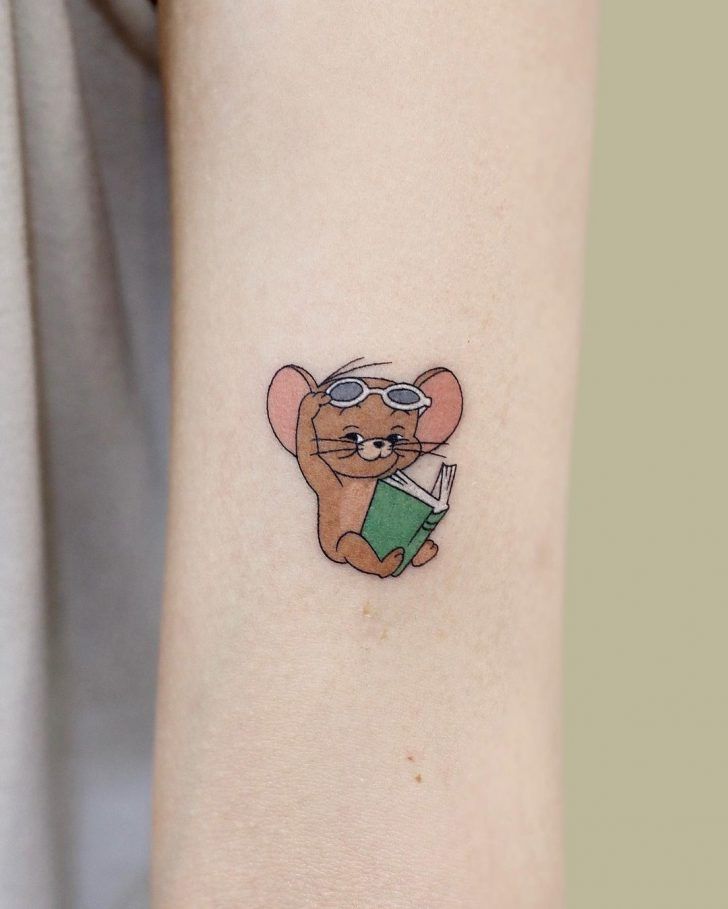 a small mouse tattoo on the left inner arm, with a book in it's hand