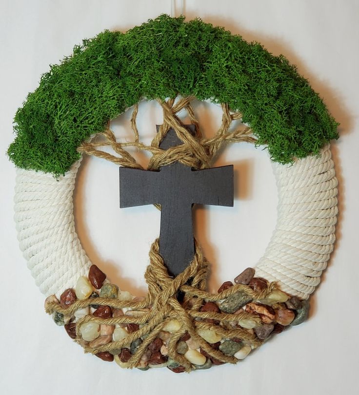 a wreath with a cross hanging from it's center surrounded by nuts and grass