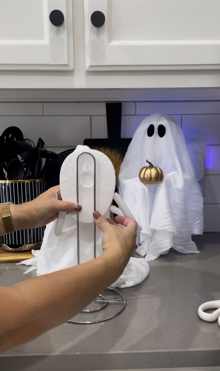 a person is holding a paper towel in front of two ghost heads