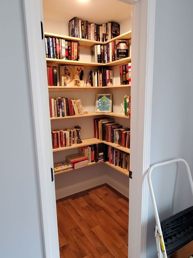 an open door leading to a book shelf with many books on it and a dolly in the corner