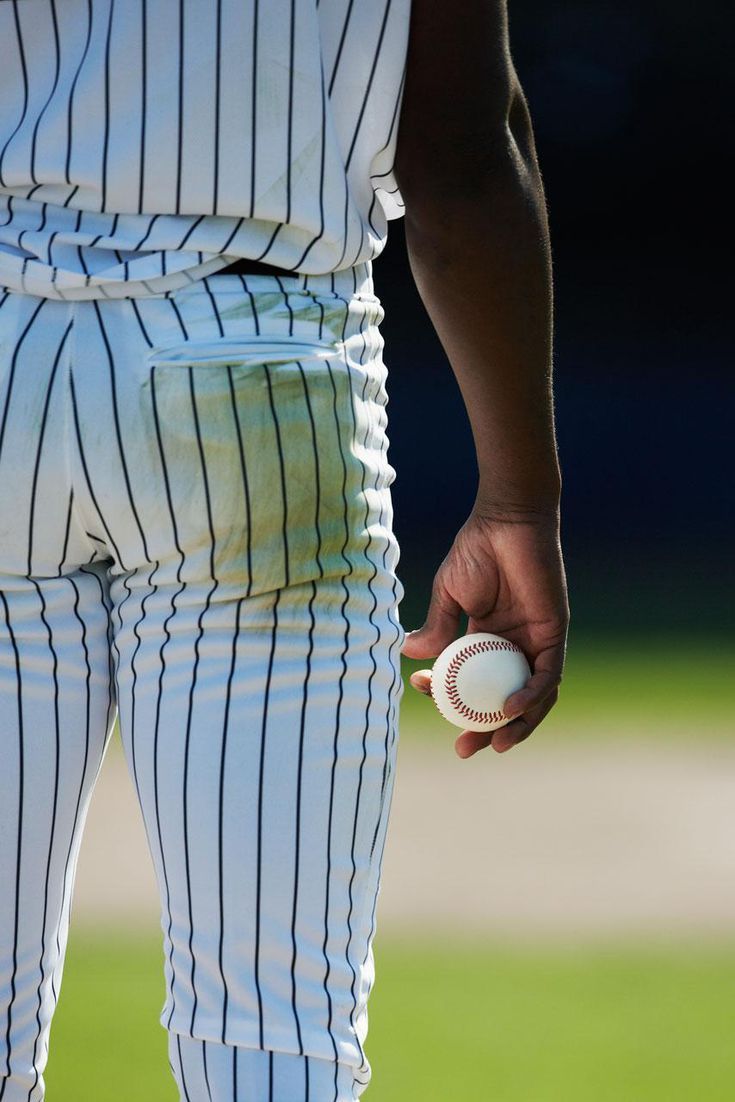 a baseball player is holding a ball in his left hand and wearing pinstripe pants