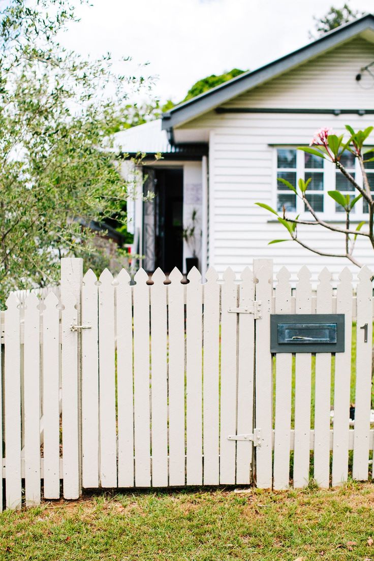 a white picket fence in front of a house with a mailbox on the side